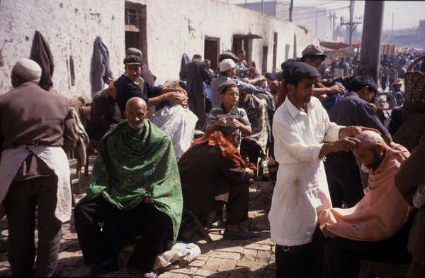 photo of China, Xinjiang province (East Turkistan), Kashi, Uygur man are shaved bold by street hairdressers on the Kashgar Sunday market