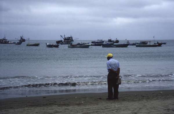 photo of Ecuador, man looking at fishing boats in the ocean around Puerto Lopez at the subtropical Ecudorian coast