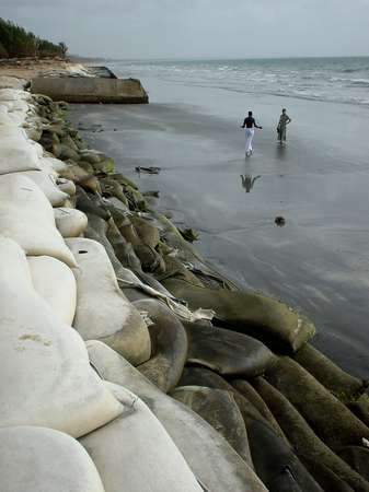 photo of The Gambia, Atlantic coast resorts, Kotu beach with sandbags, suffering from erosion, a Gambian man approaching a Western woman. Gambia has a problem with sex tourism from European women seeking contact with young local men