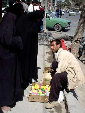 photo of Iran, man selling colored fledglings to women veiled in black during Nooruz (No Ruz, Noruz), the Persian New Year