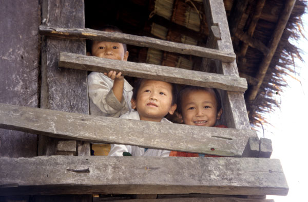 photo of Laos, rural village around Muang Khua, Laotian children looking out from a wooden house