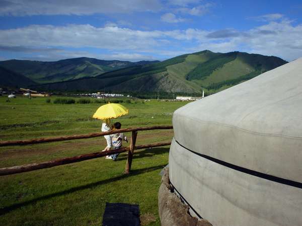 photo of Mongolia; around Terelj, hilly Mongolian landscape with two children, a yellow umbrella and a yurt (Mongolian nomad tent, yurta, ger)