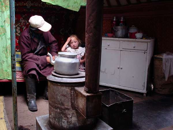 photo of Mongolia; around Terelj, man, child and tea pot on stove inside a yurt (Mongolian nomads tent, yurta, ger)