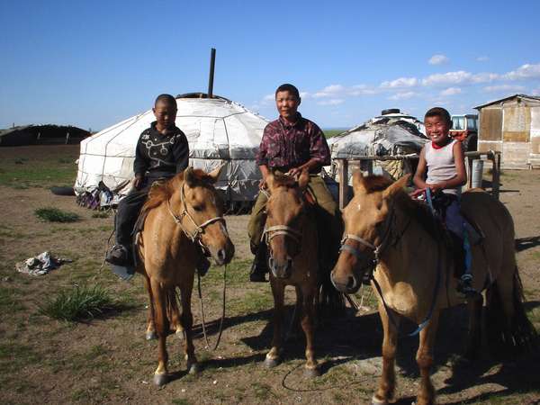 photo of Mongolia, Mongolian children on horses with nomad tents in the background