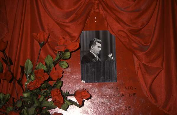 photo of Romania, Bucharest, red flowers, red curtain and black and white picture of dictator Nicolae Ceausescu in the Communist Iconography Museum