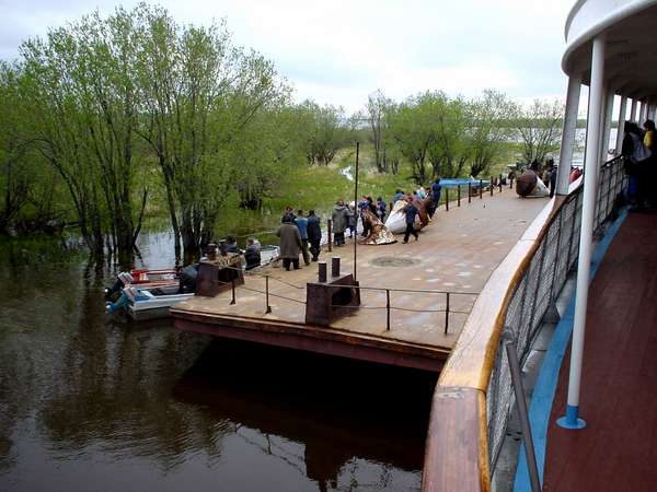 photo of Northern Siberia, on a passenger ship on the river Ob between Salekhard and Tobolsk, mooring at a floating dock, villagers of the wetlands picking up family and friends with little boats, no village in sight