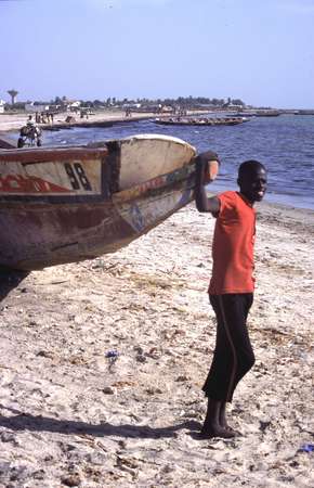 photo of Senegal, Mbour fishing village, Senegalese boy with fishermen's pirogue on the beach