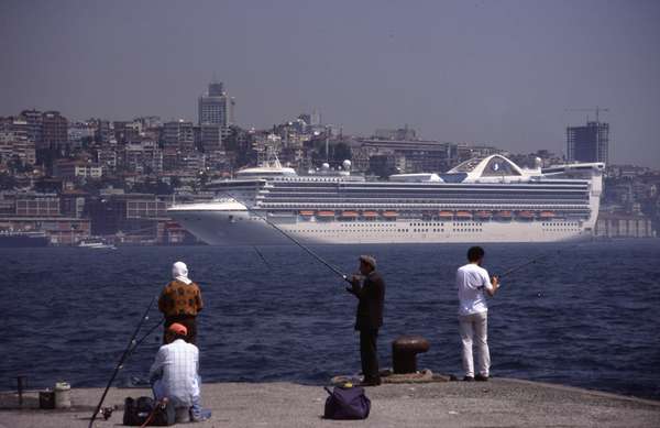 photo of Turkey, Istanbul, fishermen and fishing woman with Bosphorus and cruise ship behind