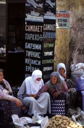 photo of Eastern Turkey, veiled Turkish woman in front of a billboard selling tickets to Batumi, Tbilisi, Kutaisi and Yerevan in Georgia and Armenia across the border