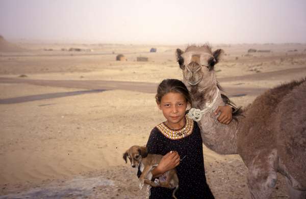 photo of Turkmenistan, Yerbent (Jerbent), Turkmen girl with camel and dog in the Kara Kum desert town of Yerbent, along the road from Ashgabat to Konye Urgench