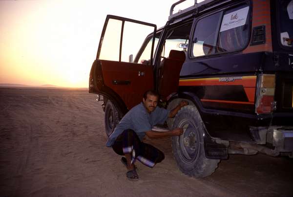 photo of Yemen, sunrise in the desert, deflating the wheels of the old Range Rover before starting the long ride through the desert to Wadi Hadramaut