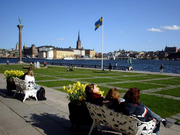 photo of Sweden, Stockholm, view on the water, the Swedish flag and the Stockholm Old Town (Gamla Stan) from the garden of the Stadshuset (City Hall)